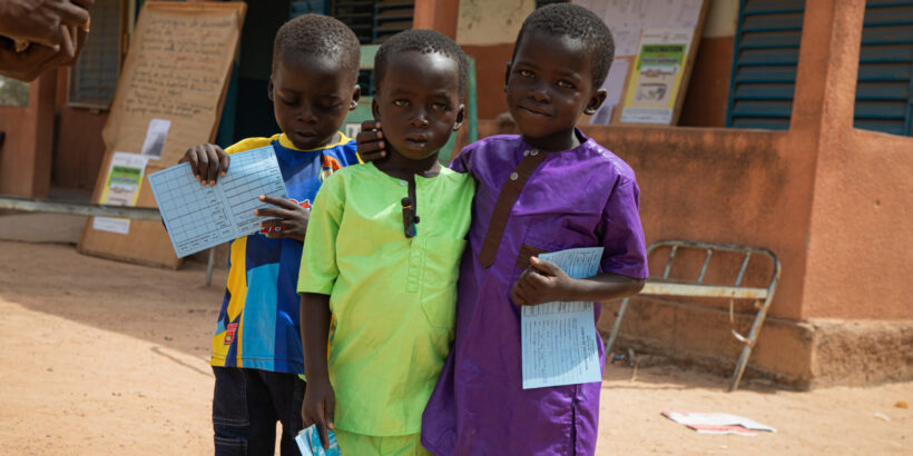 Three children hold their vaccination cards after receiving the typhoid conjugate vaccine.